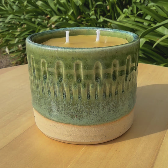 Video of pure beeswax as candle in handmade pottery spinning on a turn table so the viewer can see all angles. 